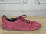 the pink sued sneakers are on a wooden table
