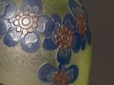 a green vase with blue and orange flowers on it