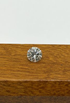 a single diamond sits on a wooden table