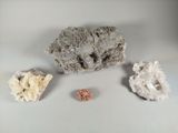 trois types de roches différents sur une surface blanche, avec un petit morceau de roche au premier plan