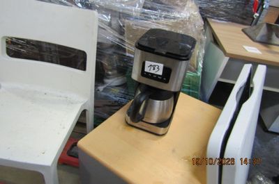 une cafetière posée sur une table à côté d'une chaise