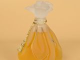 yellow glass perfume bottle with a white flower on top of it