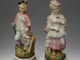 pair of porcelain figurines of a boy and a girl with a dog