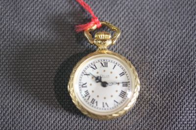 a gold pocket watch with roman numerals on it