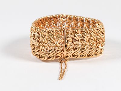 gros plan d'un bracelet en or sur une surface blanche