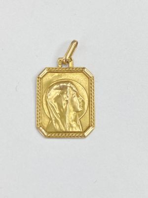 un gros plan sur un pendentif en or représentant une femme de profil