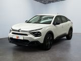 Une voiture blanche est garée dans une pièce blanche au sol noir.
