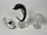 a dolphin figurine next to a pair of shoes and a wine glass