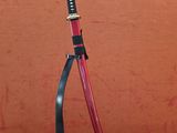 une photo d'un sabre de samouraï rouge et noir posé sur un socle noir