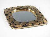 a gold plate with a mirror on it on a white surface