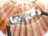 a close up of a watch with a shell in the background