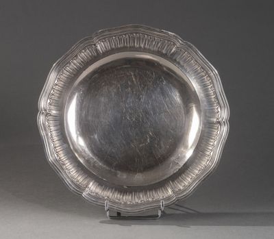 une assiette en argent posée sur un support, sur une surface grise