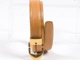 ceinture en cuir beige avec boucle dorée, présentée dans une vitrine en acrylique transparent