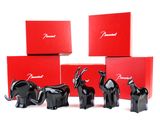 four black elephant figurines in front of red boxes on a white surface
