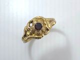 a close up of a gold ring with a red stone in it
