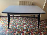 une table noire avec un plateau blanc posée sur un sol coloré