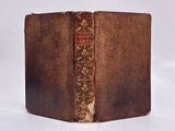 an old book with a brown cover sitting on top of a white surface