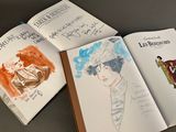 three books with drawings of people on them sitting on top of a table