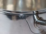 a large metal pot with a handle on a table
