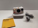 a polaroid camera sitting on a table next to a book