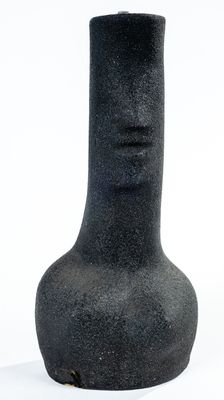 un vase noir posé sur une surface blanche