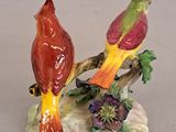 two figurines of birds sitting on a tree branch