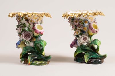 two vases with flowers on them on a white surface