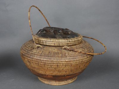 une image représentant un panier tressé muni d'une anse, sur fond gris