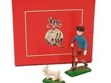une petite figurine représentant un homme et un chien devant une boîte rouge