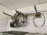 pots and pans are hanging on a rack in a kitchen