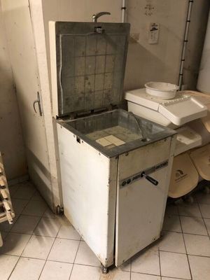 un petit réfrigérateur dans un coin d'une cuisine sale