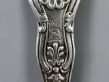 an antique spoon with a design on it sitting on a table