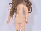 a doll with long brown hair standing on a white surface