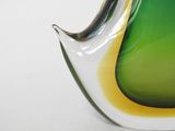 a green and yellow glass vase sitting on a white surface