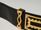 black leather belt with gold metal buckle on a white surface