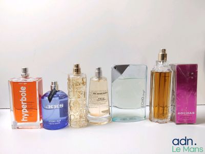 plusieurs types de flacons de parfum alignés sur une surface blanche