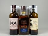 trois bouteilles de whisky sont alignées sur une surface blanche