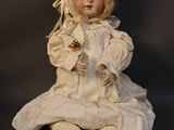 a doll that is sitting on the ground with a flower in her hand