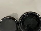 two black bottles of wine sitting on top of a white surface