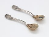 pair of silver spoons sitting on top of a white surface