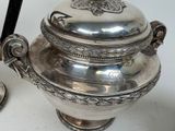 a silver pot with a spoon on it next to a spoon