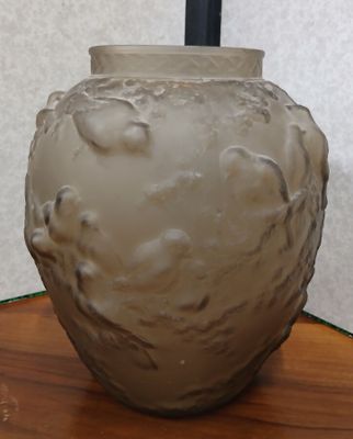 un vase blanc posé sur une table, muni d'une anse noire