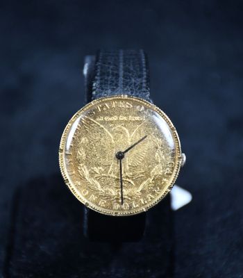 une photo en gros plan d'une montre-bracelet sur laquelle repose une pièce d'or
