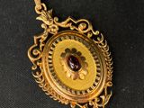 a close up of a gold locke with a red stone in it