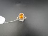 une bague sertie d'un saphir orange et de diamants, posée sur un fond noir
