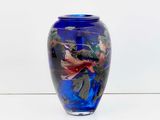 a blue vase with a bird on it sitting on a table