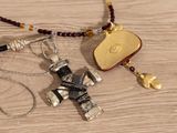 a necklace with a cross on it next to a purse on a table
