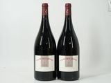 two bottles of red wine sitting next to each other on a white surface