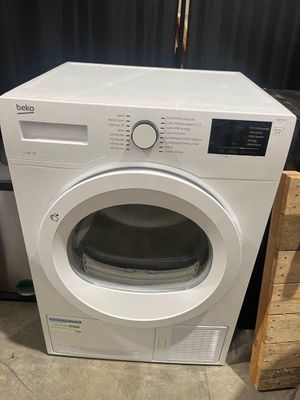 une machine à laver blanche posée sur un plan de travail, à côté d'une caisse en bois