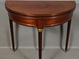 an oval mahogany table with brass legs and a curved top